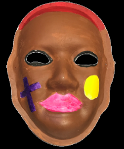 Unmasking Brain Injury mask painted brown with a purple cross, pink lips and a yellow oval