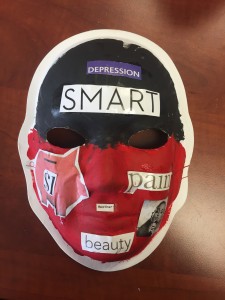 Unmasking Brain Injury mask painted black and red with cut out text on top