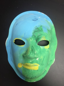 Unmasking Brain Injury mask painted green and blue with yellow lips