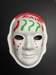 Unmasking Brain Injury mask painted with red and green question marks and the word "pain"