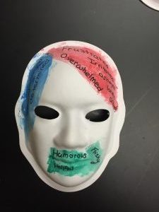 Unmasking Brain Injury mask painted with red, blue and green sections with text written on them