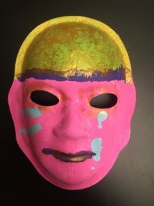 Unmasking Brain Injury mask painted pink with a gold forehead with a purple line