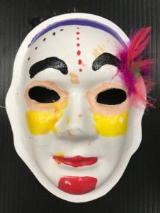 Unmasking Brain Injury mask painted with facial features in yellow, peach, red and purple