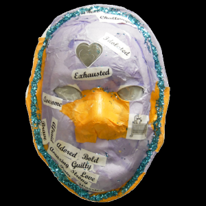 Unmasking Brain Injury mask painted pale purple with an orange nose and text