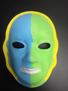 Unmasking Brain Injury mask painted half green and half blue with yellow around the edge