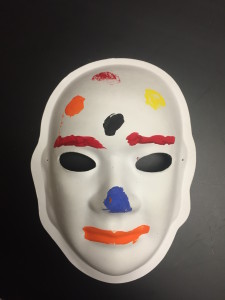 Unmasking Brain Injury mask painted with red eyebrows, orange lips a blue spot on the nose and some other spots