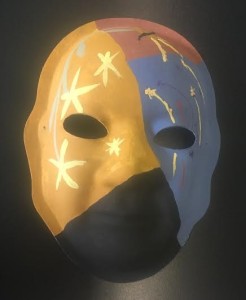 Unmasking Brain Injury mask painted in orange, blue, black and red with yellow stars