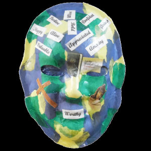 Unmasking Brain Injury mask painted blue, green and yellow with text on top