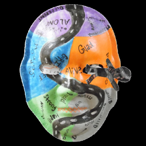 Unmasking Brain Injury mask painted with orange, green, blue, purple and a road painted through the middle