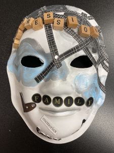 Unmasking Brain Injury mask painted blue and gray with scrabble pieces and text stickers