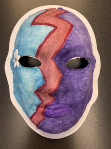 Unmasking Brain Injury mask painted purple and blue with a red zig zag and a flower