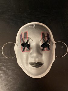 Unmasking Brain Injury mask painted with black lines and xs over the eyes