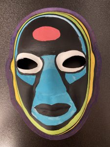 Unmasking Brain Injury mask painted black with blue, red and yellow sections