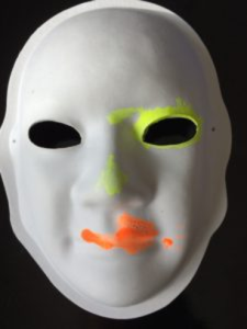 Unmasking Brain Injury mask painted with yellow around the right eye and orange on the lips