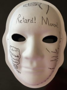 Unmasking Brain Injury mask painted with derogatory terms