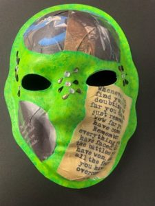 Unmasking Brain Injury mask painted green with magazine pages collaged