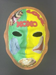 Unmasking Brain Injury mask painted green and yellow with magazine images and love and xoxo