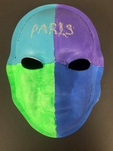 Unmasking Brain Injury mask painted with two blue section, a purple section and a bright green section with "Paris" on the forehead