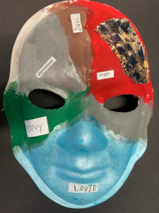 Unmasking Brain Injury mask painted with blue, green, gray, red and silver sections