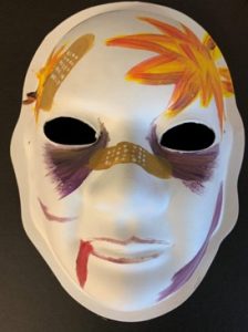 Unmasking Brain Injury mask painted with purple sections and gold painted bandaids and an orange flame