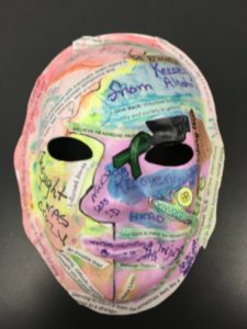 Unmasking Brain Injury mask painted with multicolored sections and lots of text