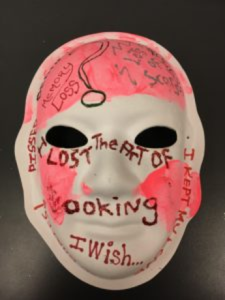 Unmasking Brain Injury mask painted with pink sections and words