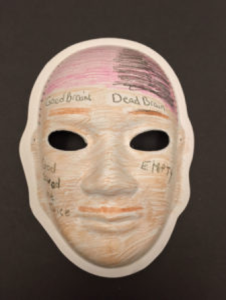 Unmasking Brain Injury mask with hand drawn mustache and eyebrows and words written on it
