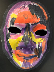 Unmasking Brain Injury mask painted in orange, black, purple and yellow