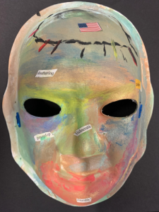 Unmasking Brain Injury mask painted with soft rainbow colors with an American flag and text
