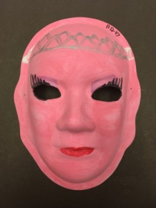 Unmasking Brain Injury mask painted pink with eyelashes, a crown and red lips