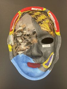 Unmasking Brain Injury mask painted with black and blue and images collaged on with the word "love"