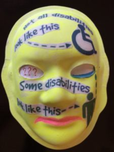 Unmasking Brain Injury mask painted yellow with text about disabilities