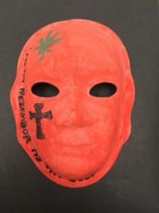 Unmasking Brain Injury mask painted red with a black cross and text