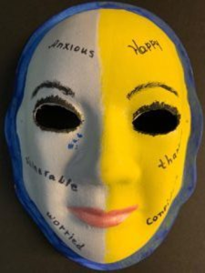 Unmasking Brain Injury mask painted yellow and gray with text written on top