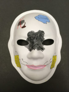 Unmasking Brain Injury mask painted with black, blue and yellow segments