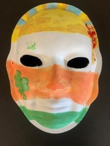 Unmasking Brain Injury mask painted with yellow, orange and green stripes