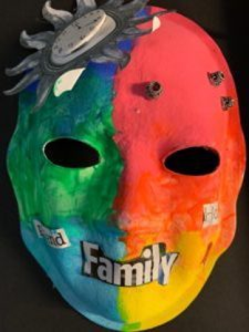 Unmasking Brain Injury mask painted with red, yellow, blue and green sections and the text "family"