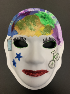 Unmasking Brain Injury mask painted with multicolored glitter paint