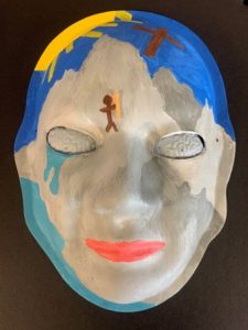 Unmasking Brain Injury mask painted with white, blue and yellow with brains as eyes