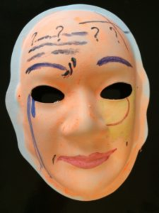 Unmasking Brain Injury mask painted orange with black text and lines