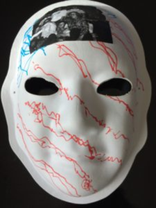 Unmasking Brain Injury mask painted white with blue and red lines drawn on it and a photo on the forehead