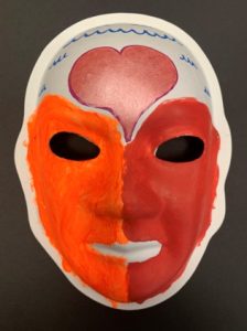 Unmasking Brain Injury mask painted red, orange and white with a heart on the forehead