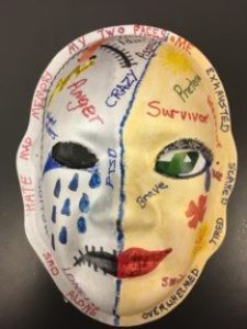 Unmasking Brain Injury mask painted yellow and white with text