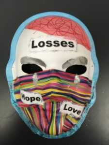 Unmasking Brain Injury mask painted with multicolor stripes and printed text