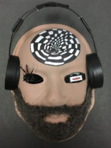 Unmasking Brain Injury mask painted with a face with a beard and headphones and an optical illusion on the forehead