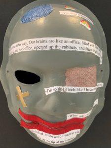 Unmasking Brain Injury mask painted gray with printed text on top