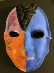 Unmasking Brain Injury mask painted with blue, orange, pink and black sections
