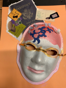 Unmasking Brain Injury mask painted with pearl white and pink with gold painted glasses on a collaged background