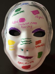 Unmasking Brain Injury mask painted with small colored blotches and text