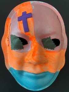 Unmasking Brain Injury mask painted with orange, blue and pink sections and a purple cross